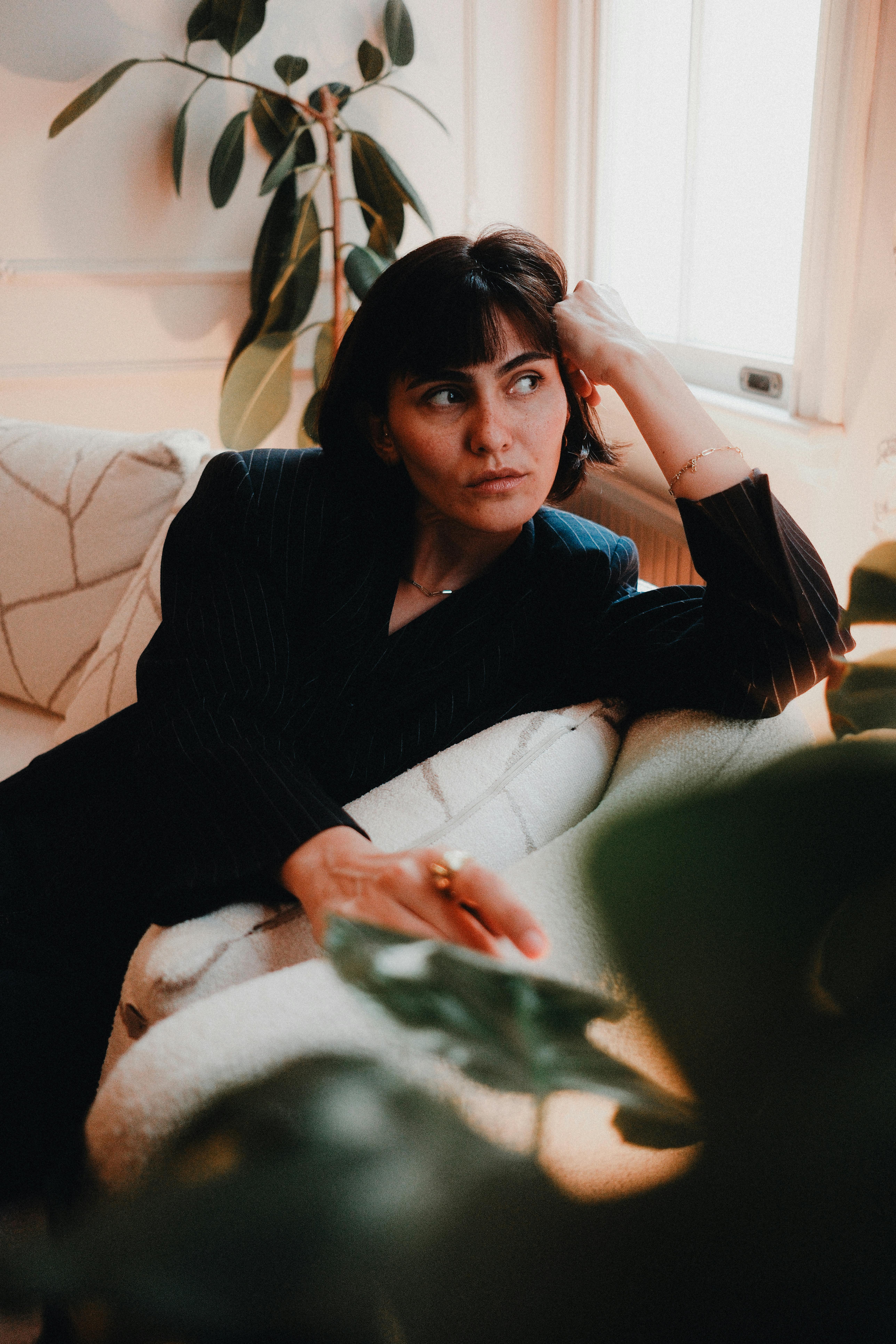 A relaxed woman sitting in a bright room with natural light.