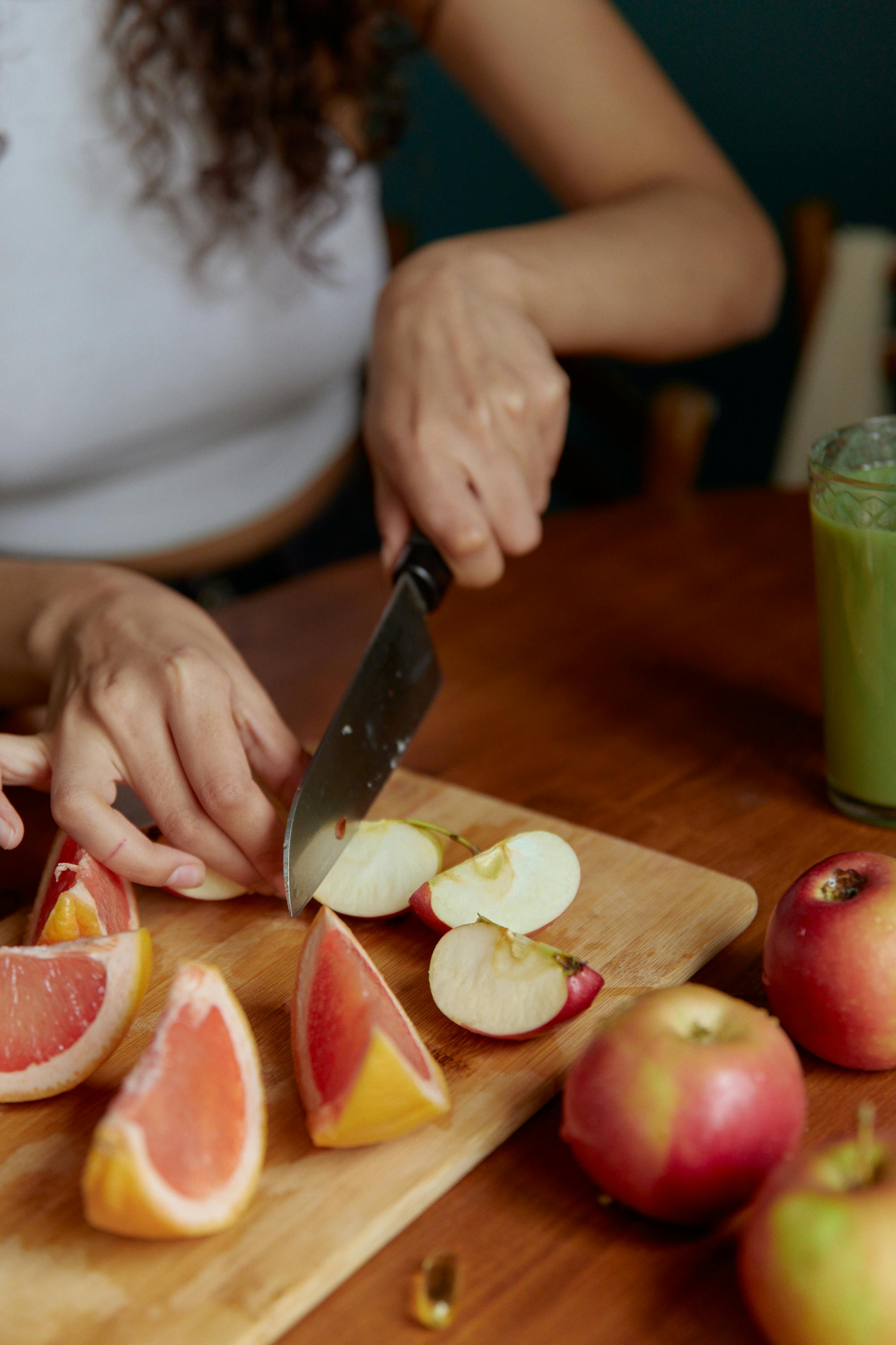 Hands preparing fruit on a cutting board in natural kitchen light.