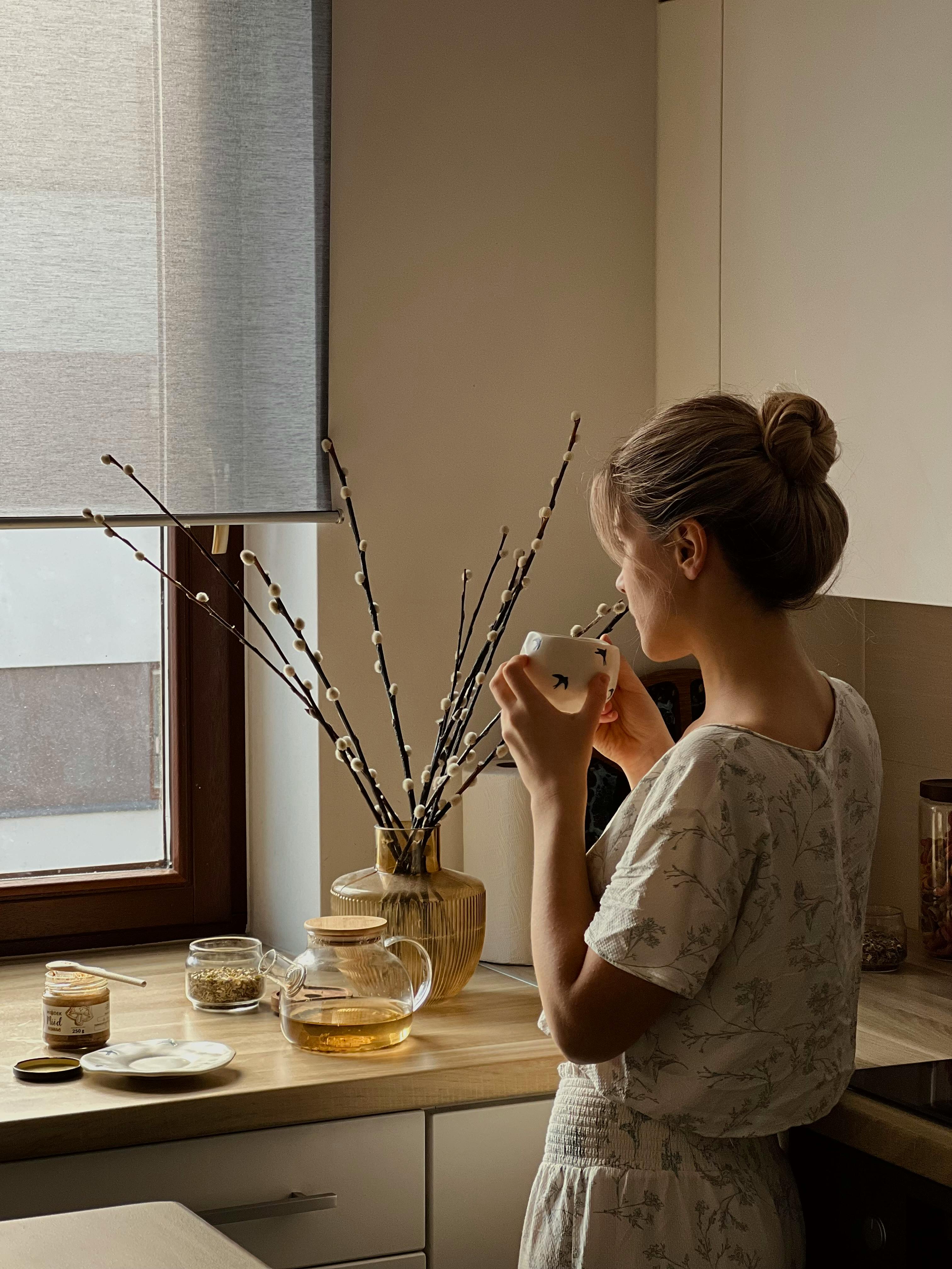 A woman enjoying tea in soft morning window light.